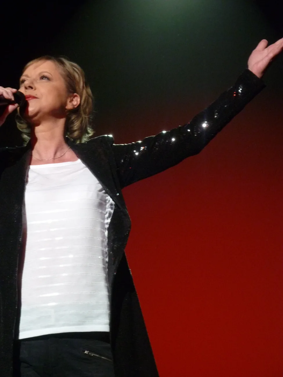 Dorothée chante sur la scène de l’Olympia le 17 avril 2010, tenant un microphone.